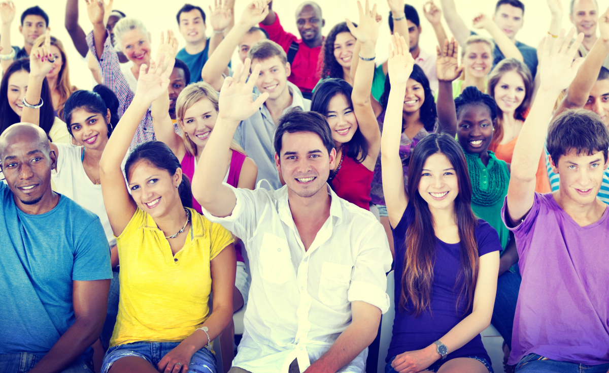 This is an image of a group of people with their hands raised, volunteering.