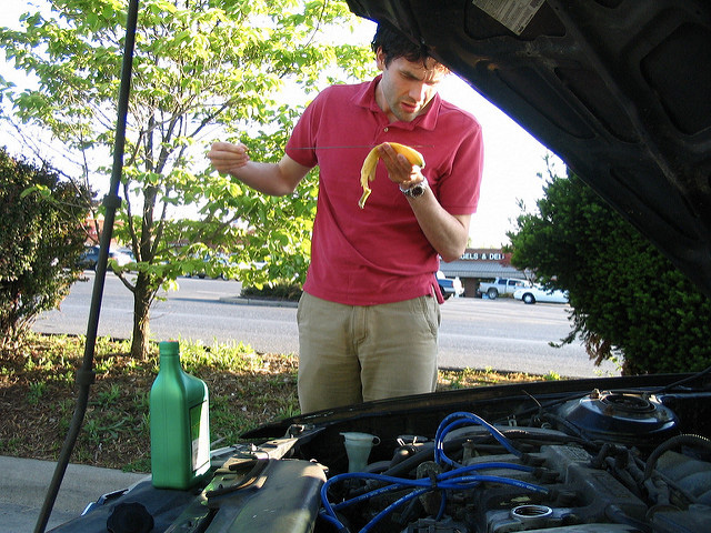 This is an image of a man adding oil to his car.