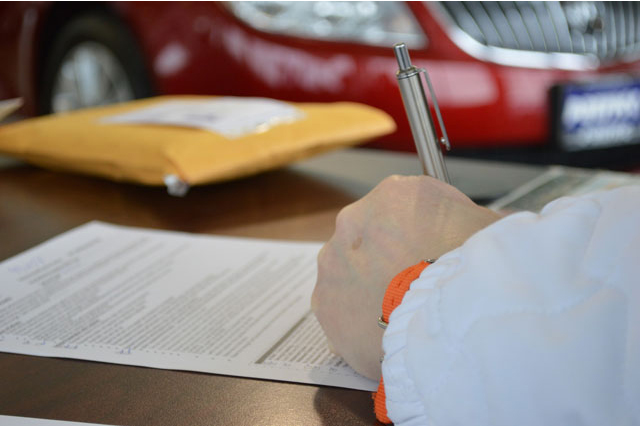 This is an image of someone signing papers at an auto dealership.