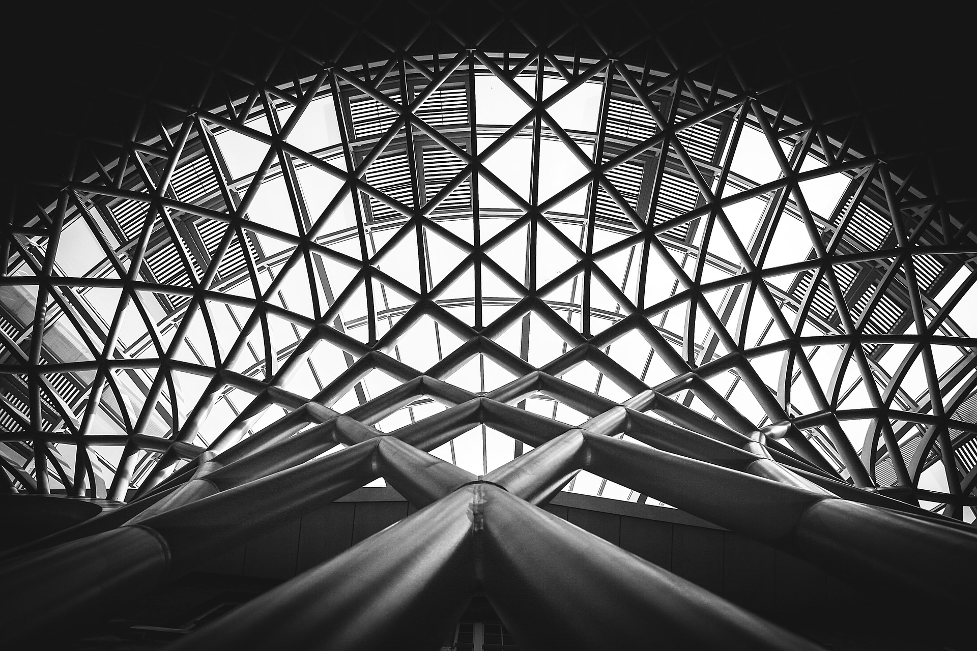 An image of windows on the roof of a building being supported by a network of beams that create a variety of shapes.