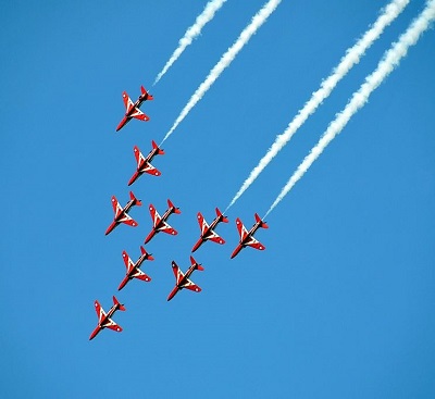 An image of an air show. There are 7 planes with coloured smoke trails.