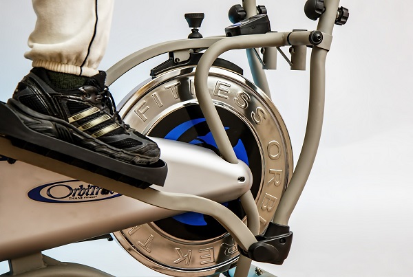 An image of a person's foot and leg on an elliptical trainer at the gym.
