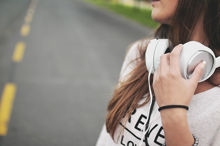 An image of a girl walking down the street with her headphones.
