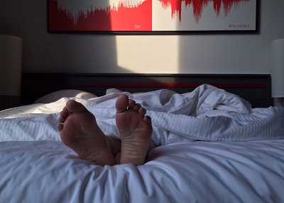 An image of two feet sticking out from under the sheets, as the owner of those feet is asleep.