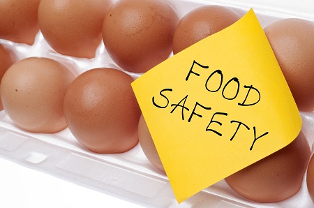 This is a picture of an open carton of eggs  with a sticker on it that reads, Food Safety.