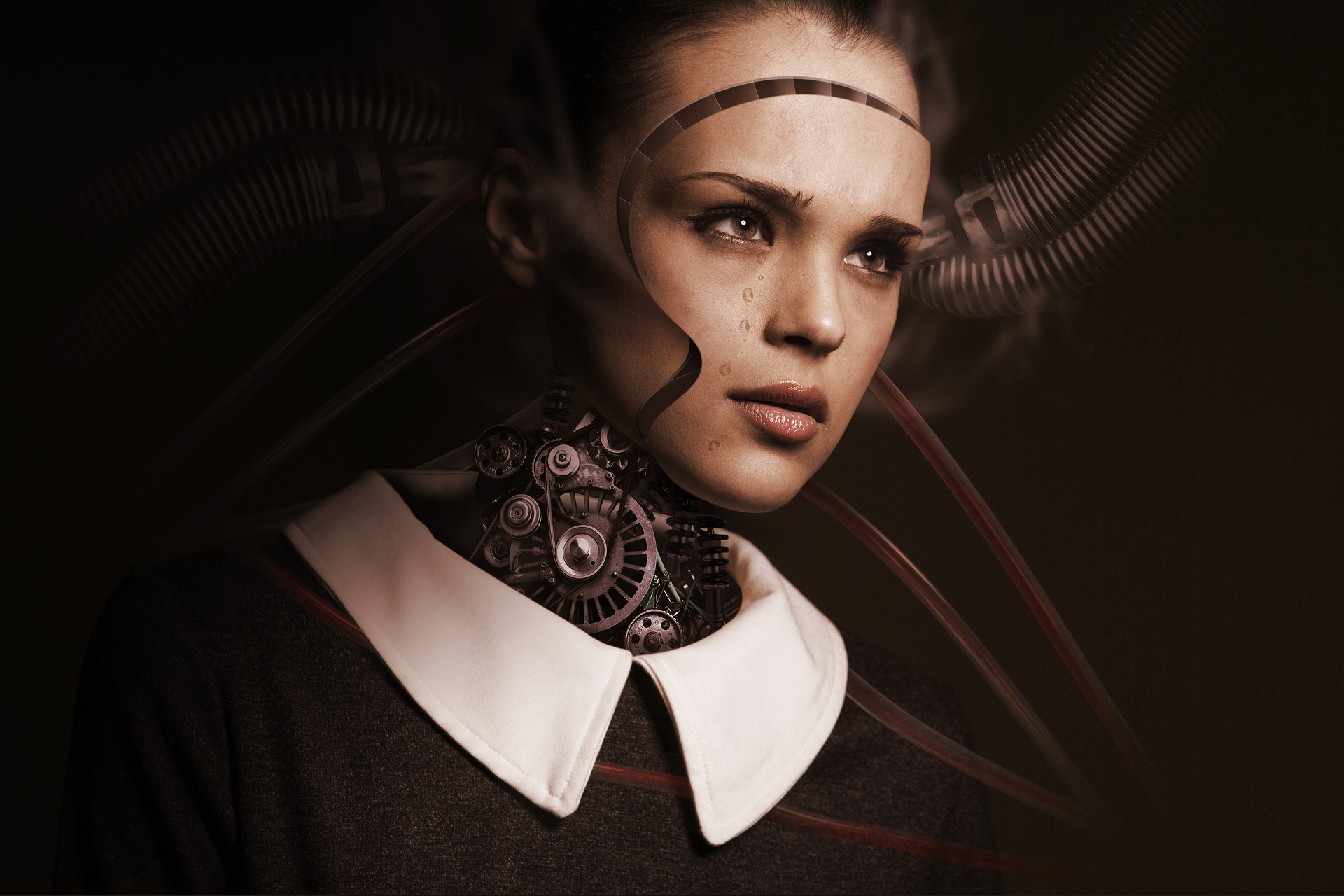 This is an image of a cyborg on a darkly shaded background. The face is that of a human girl, but you can see a border around the face that indicates it can be removed. The neck region is a cluster of gears and machinery. She is wearing a dark dress with a large, white collar. Only the head and shoulders of the cyborg are visible in the image.