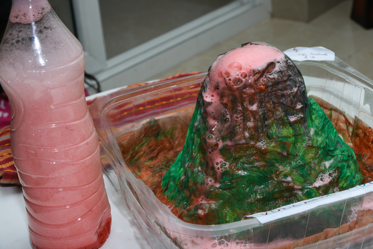 a paper mache shaped volcano. Pink foam is coming up out of the volcano vent.