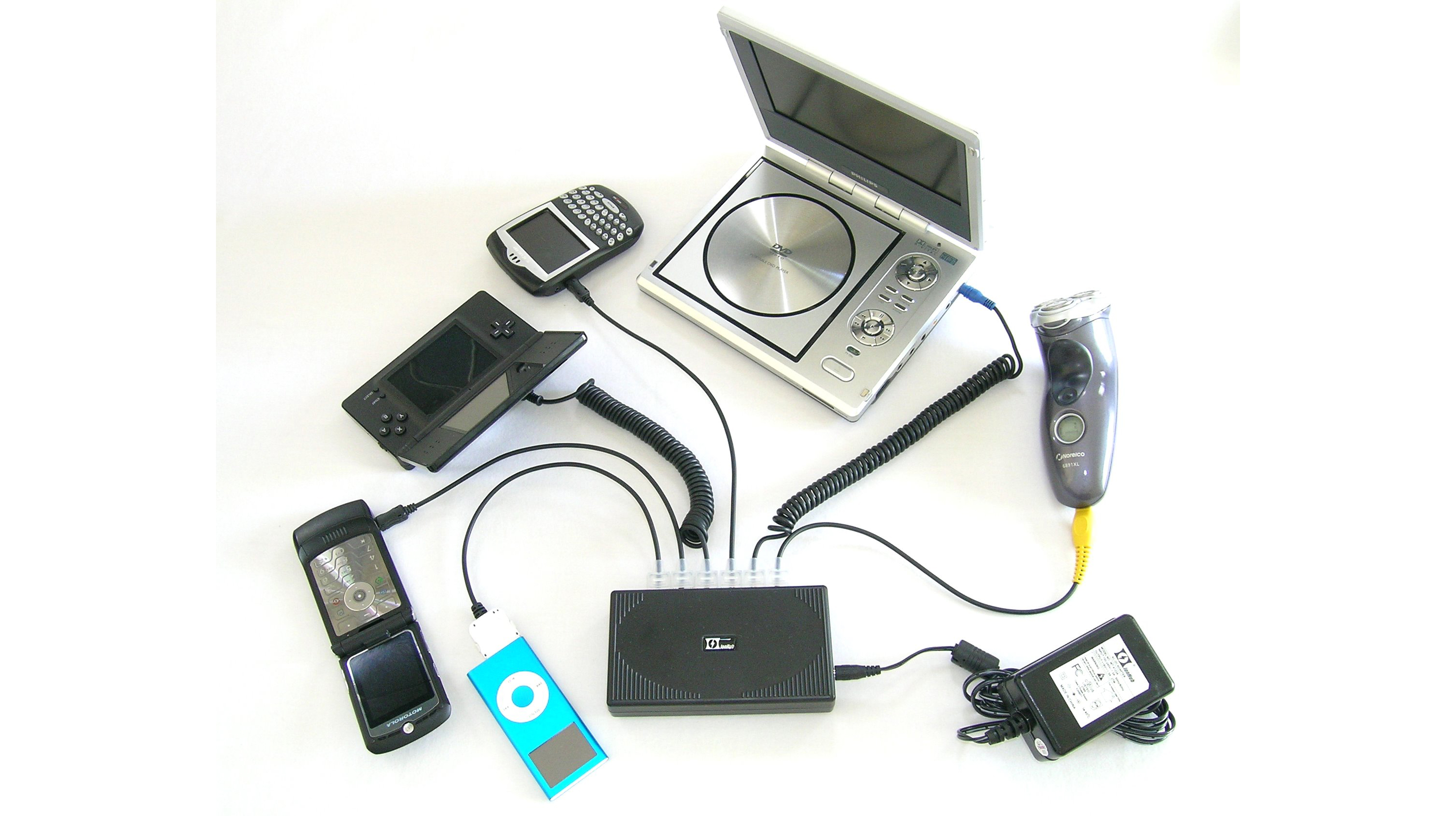 This is a photo of a number of electronics such as cell phones, video player, mp3 player and an electric shaver.