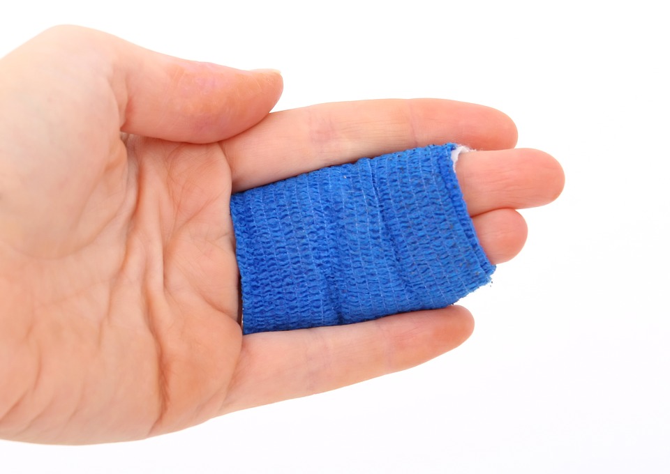 This is an image of a hand whose middle and ring fingers are bound together with a blue bandage. 