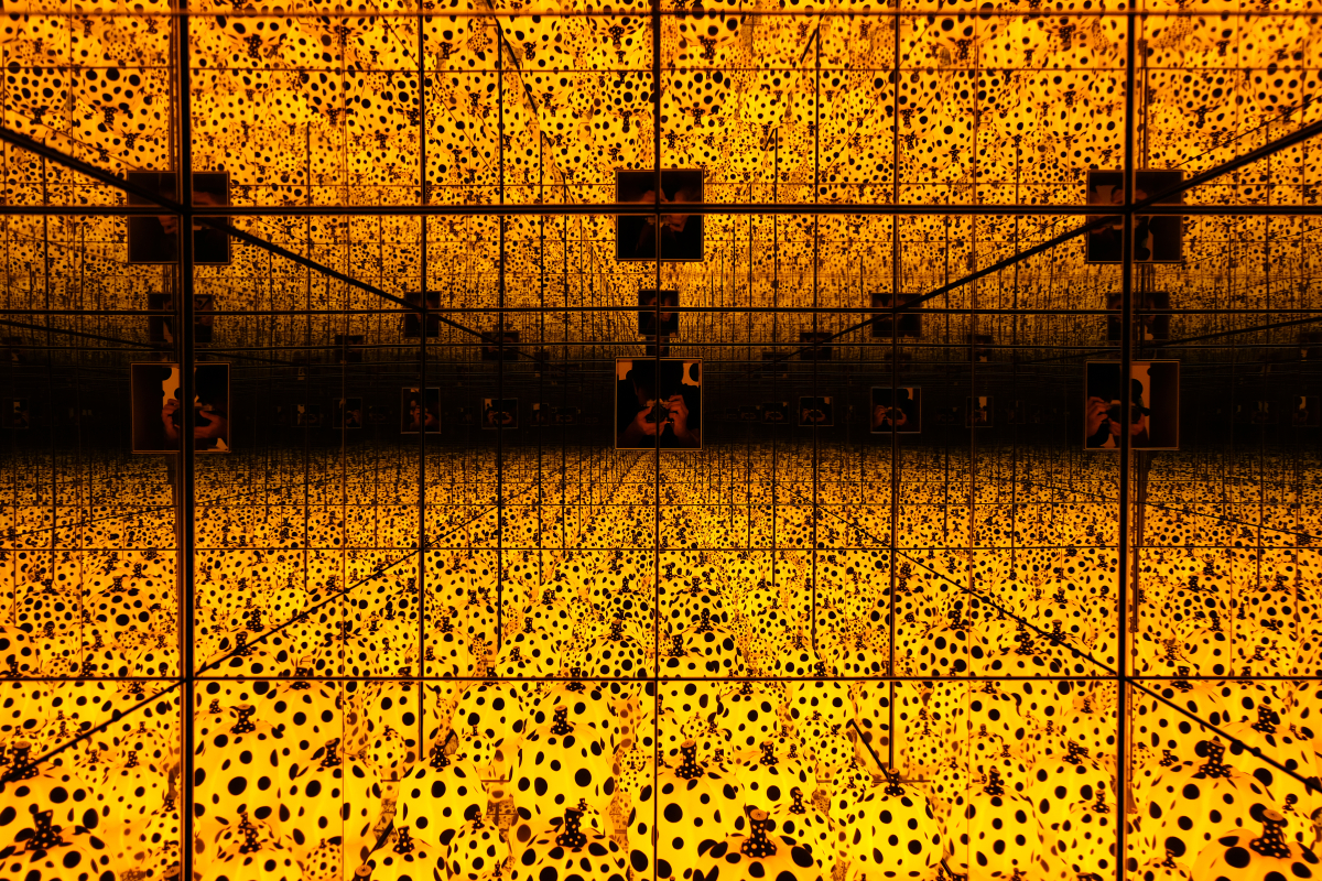 This is an image of Yayoi Kusama’s Infinity Mirrors. There are yellow mushrooms covered in black spots reflected an infinite number of times in the distance.