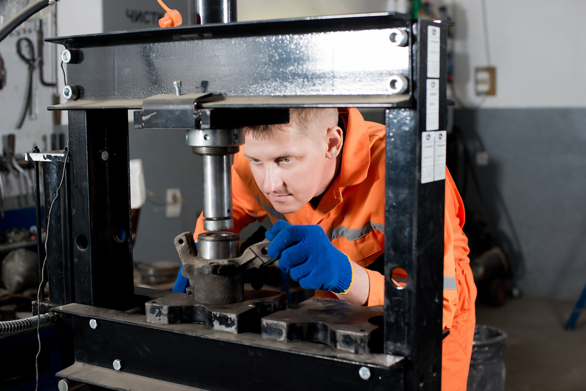 This image depicts a worker using a hydraulic press.