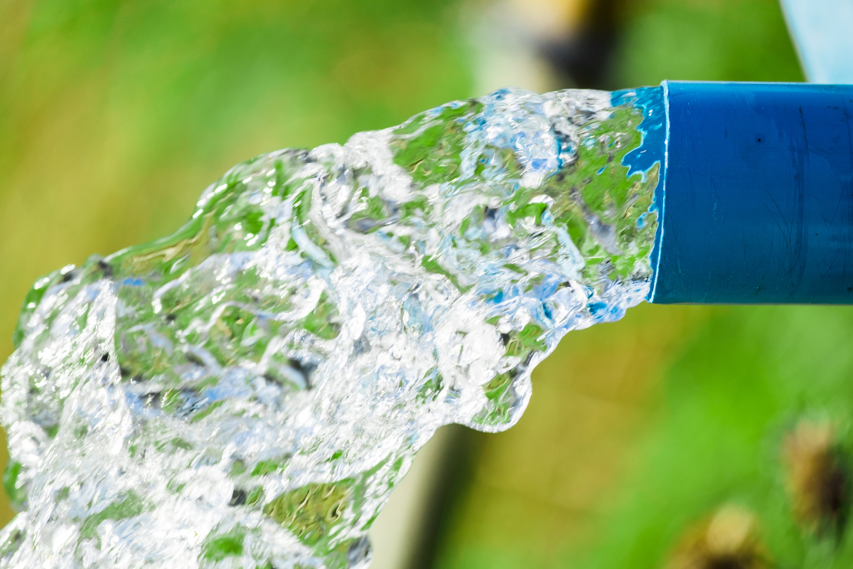 This image depicts water flowing from the end of a blue pipe.