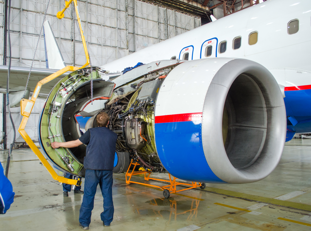 This image depicts employees replacing an engine on a plane.