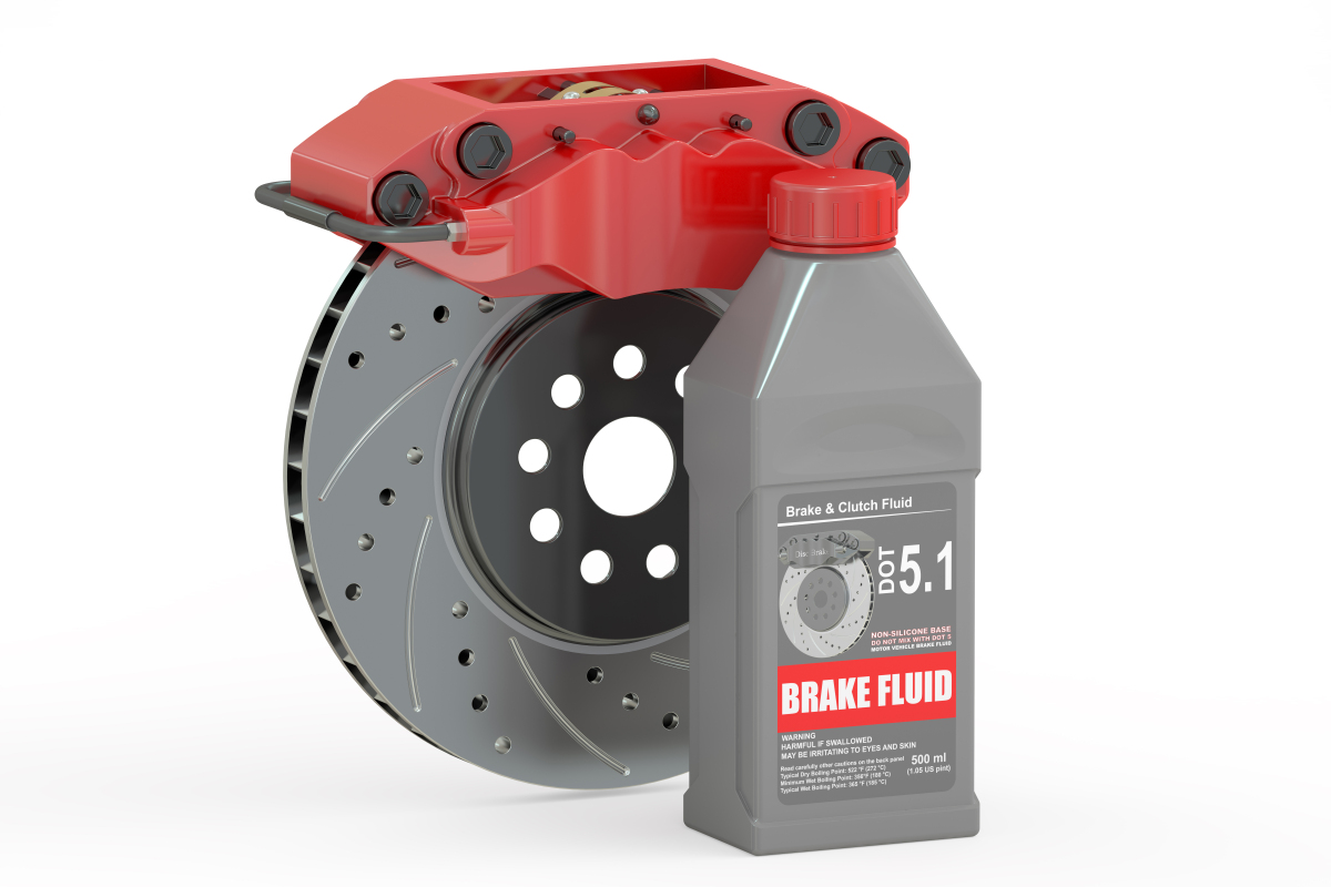 This image depicts a brake rotor, calliper, and bottle of brake fluid