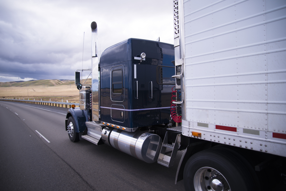 This image depicts a semi truck driving down a highway. 