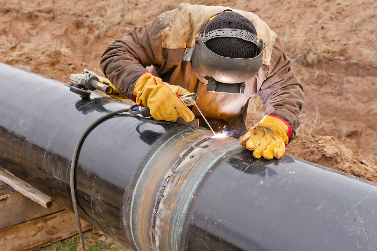 This image depicts a welder working on a pipeline.