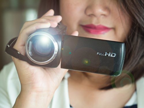This image depicts a woman holding a video camera.
